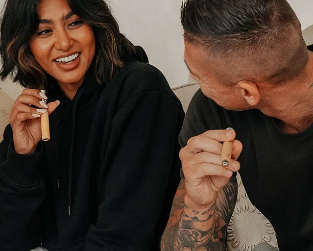 Two people sitting together, one holding a small object.